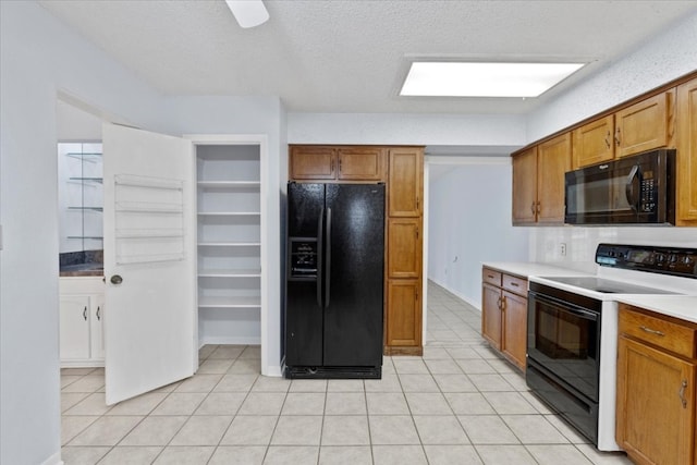 kitchen featuring black appliances, light tile patterned flooring, and a textured ceiling