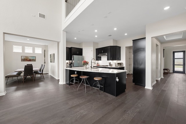 kitchen featuring dark wood-type flooring, sink, stainless steel fridge, kitchen peninsula, and a breakfast bar area