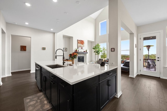 kitchen featuring dishwasher, sink, an island with sink, and dark wood-type flooring