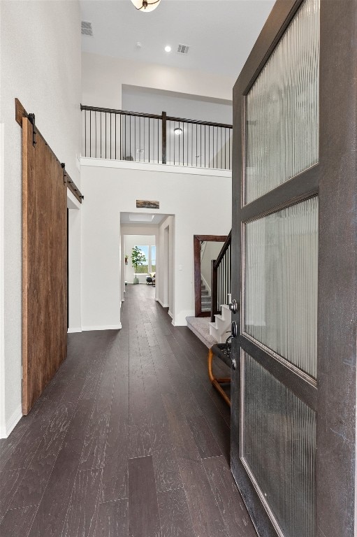 entrance foyer featuring a barn door, dark hardwood / wood-style flooring, and a towering ceiling