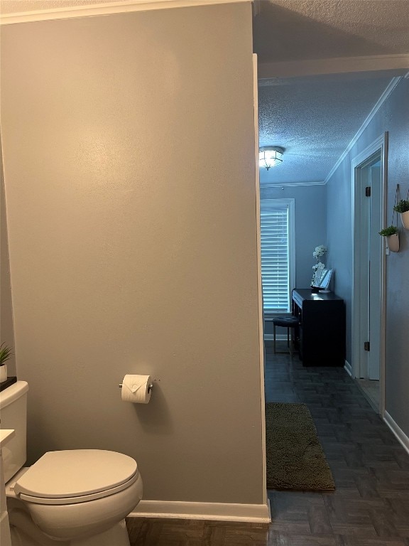 bathroom featuring parquet flooring, a textured ceiling, toilet, and crown molding