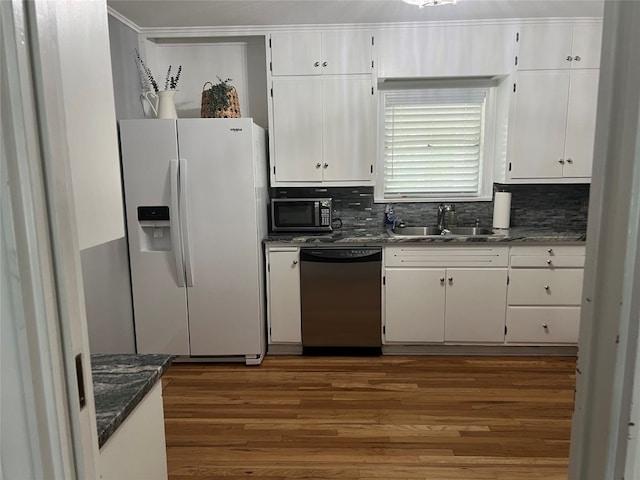 kitchen with dark wood-type flooring, appliances with stainless steel finishes, sink, white cabinets, and dark stone counters