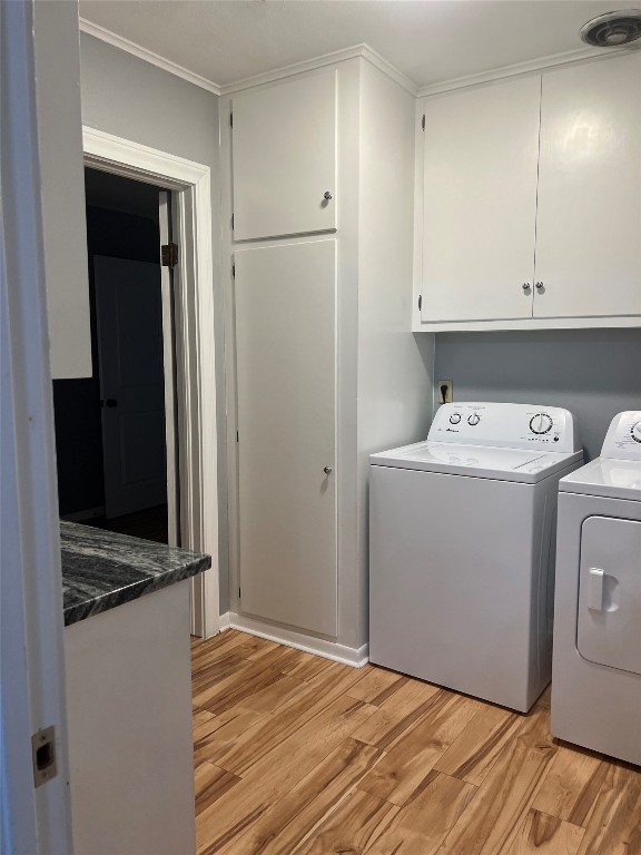 washroom featuring independent washer and dryer, light hardwood / wood-style floors, cabinets, and crown molding