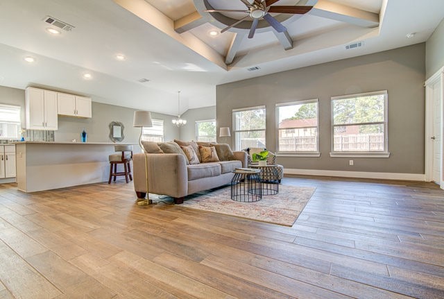 living room with ceiling fan with notable chandelier, a healthy amount of sunlight, and light wood-type flooring