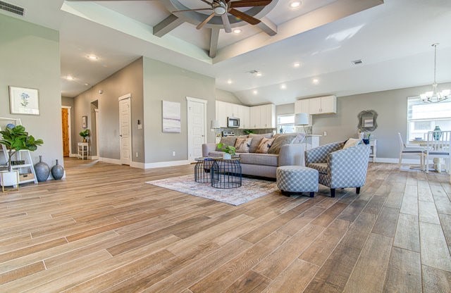 living room featuring ceiling fan with notable chandelier and light hardwood / wood-style floors