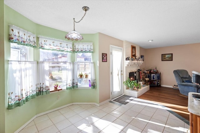 tiled entrance foyer featuring a wealth of natural light, a brick fireplace, brick wall, and a textured ceiling