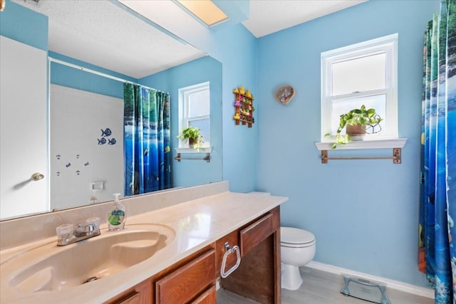 bathroom featuring a textured ceiling, hardwood / wood-style floors, toilet, and vanity with extensive cabinet space