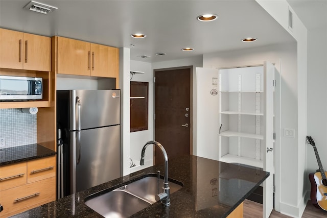 kitchen featuring light brown cabinetry, dark stone counters, sink, and stainless steel appliances