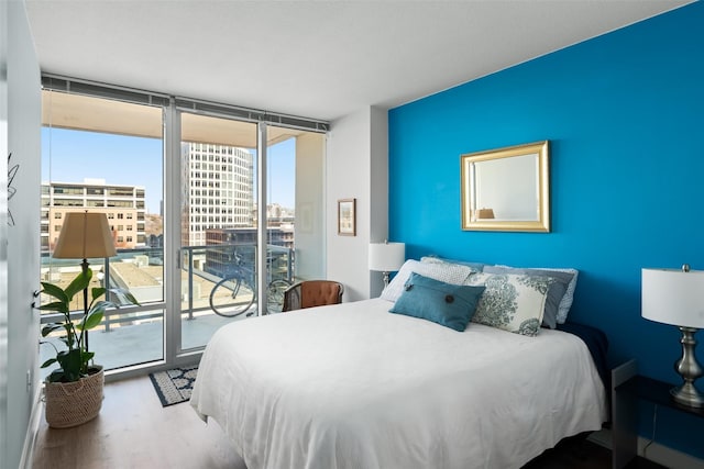 bedroom with hardwood / wood-style flooring, expansive windows, and access to outside