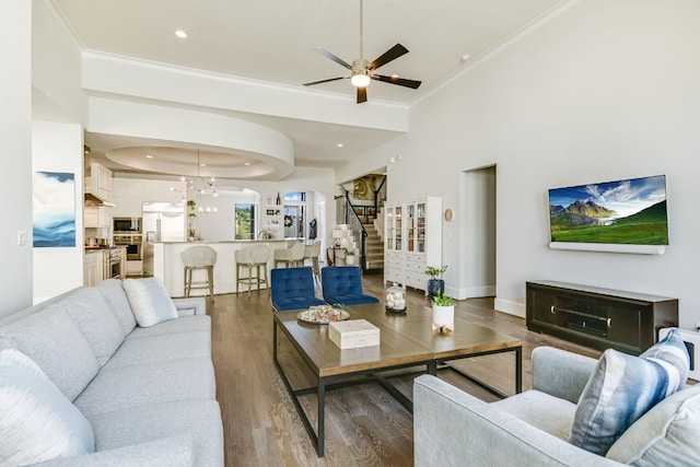 living area with ornamental molding, stairs, baseboards, and wood finished floors