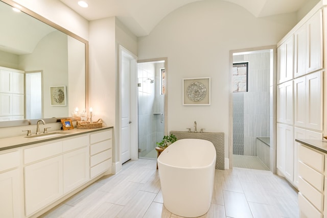 bathroom with vaulted ceiling, vanity, and independent shower and bath