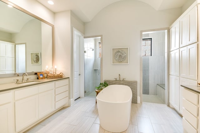 full bathroom featuring a walk in shower, vaulted ceiling, a soaking tub, and vanity