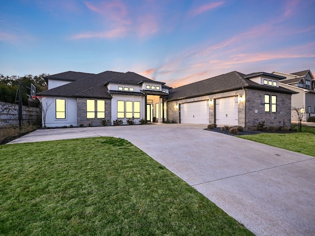 prairie-style house with concrete driveway, fence, a garage, stone siding, and a front lawn