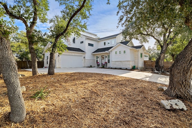 traditional home with a garage, stone siding, fence, and driveway