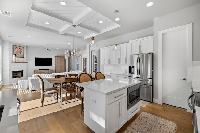 kitchen with light hardwood / wood-style flooring, white cabinets, a center island, stainless steel appliances, and a fireplace