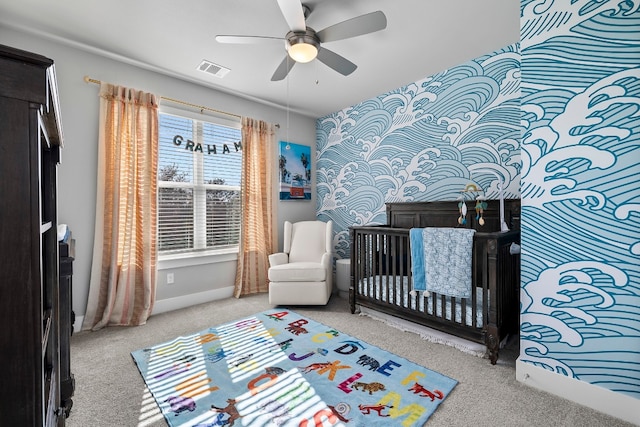 bedroom featuring light carpet, a nursery area, and ceiling fan