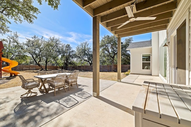 view of patio featuring ceiling fan, a playground, a fenced backyard, and outdoor dining space