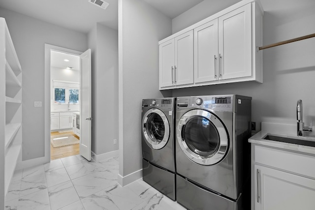 laundry room featuring washer and clothes dryer, sink, cabinets, and light hardwood / wood-style floors