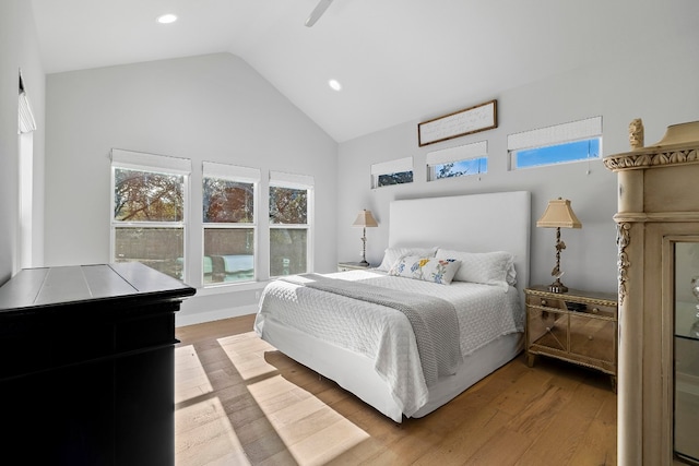 bedroom with light wood-type flooring and high vaulted ceiling