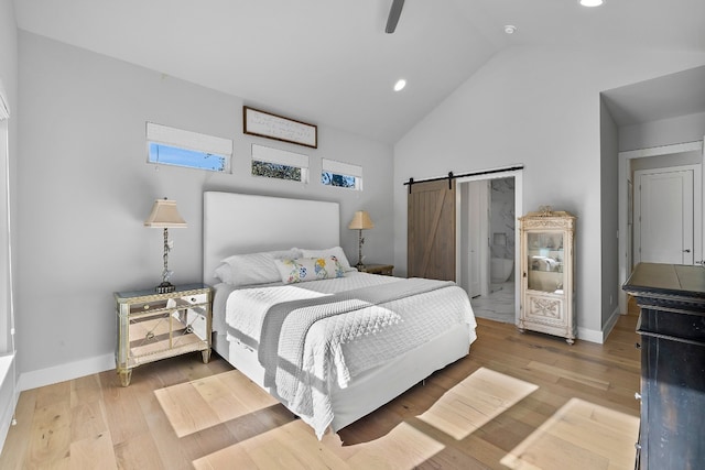 bedroom featuring connected bathroom, a barn door, light wood-type flooring, high vaulted ceiling, and ceiling fan