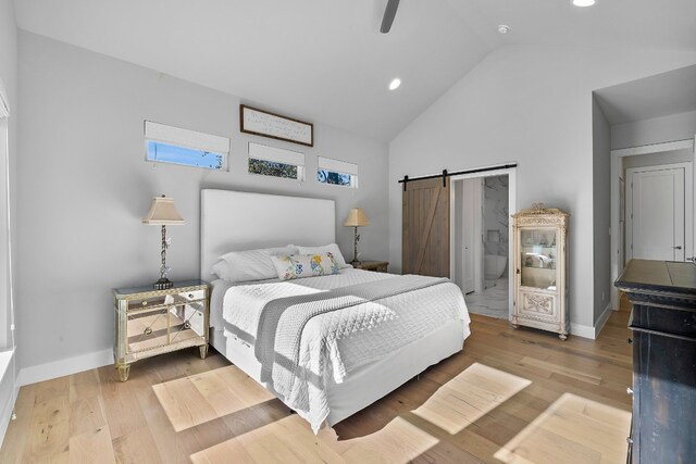 bedroom with wood finished floors, baseboards, and a barn door