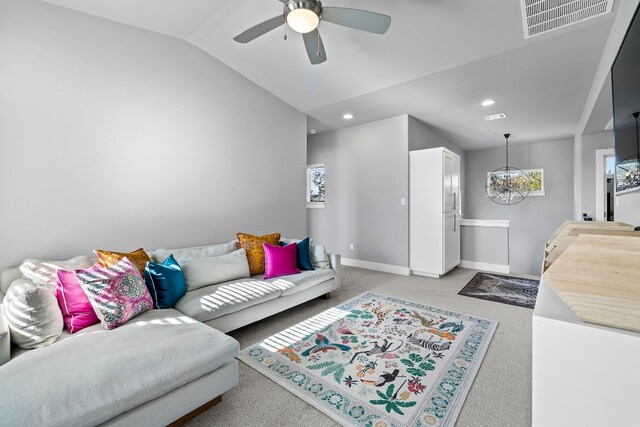 carpeted living room with ceiling fan with notable chandelier and lofted ceiling