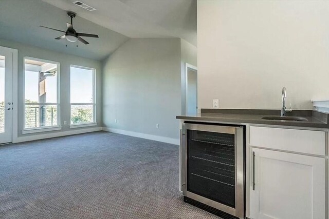 bar with beverage cooler, visible vents, light colored carpet, vaulted ceiling, and a sink