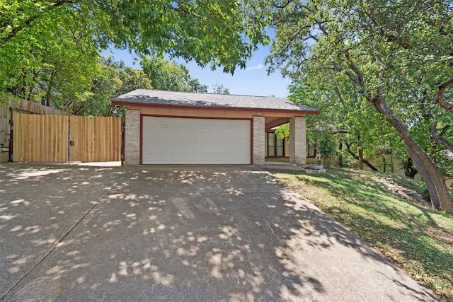 single story home featuring an attached garage, driveway, fence, and brick siding