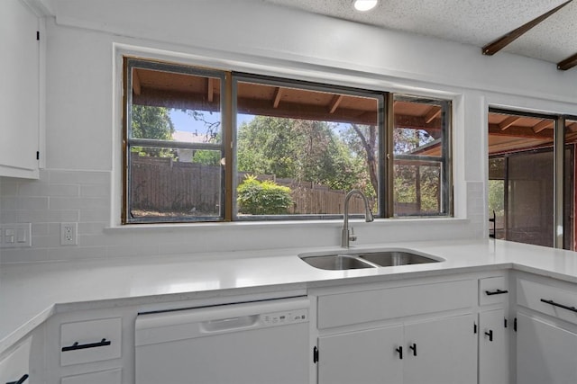 kitchen featuring light countertops, a sink, tasteful backsplash, white cabinetry, and dishwasher