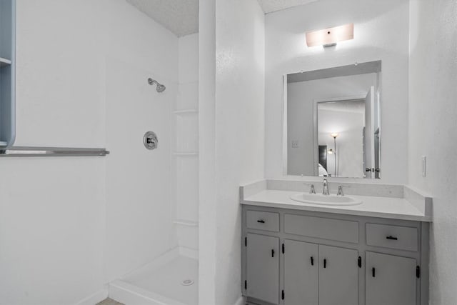 bathroom with baseboards, a shower stall, and vanity
