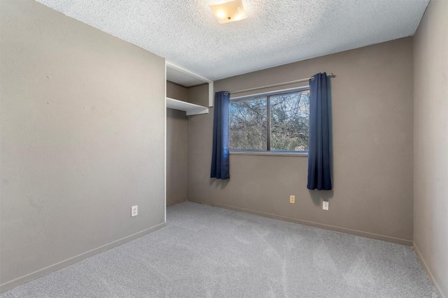 spare room featuring a textured ceiling, carpet flooring, and baseboards