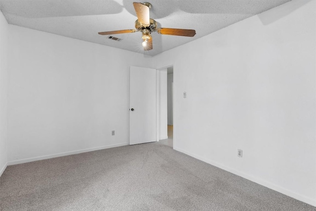 carpeted spare room with baseboards, visible vents, and ceiling fan
