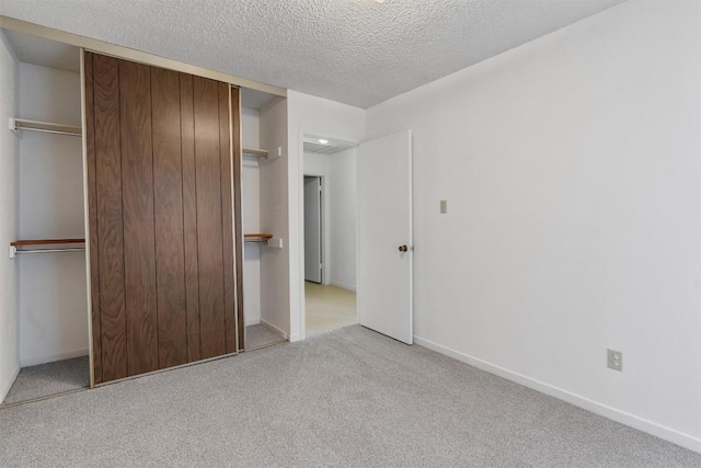unfurnished bedroom with baseboards, carpet flooring, a textured ceiling, and a closet