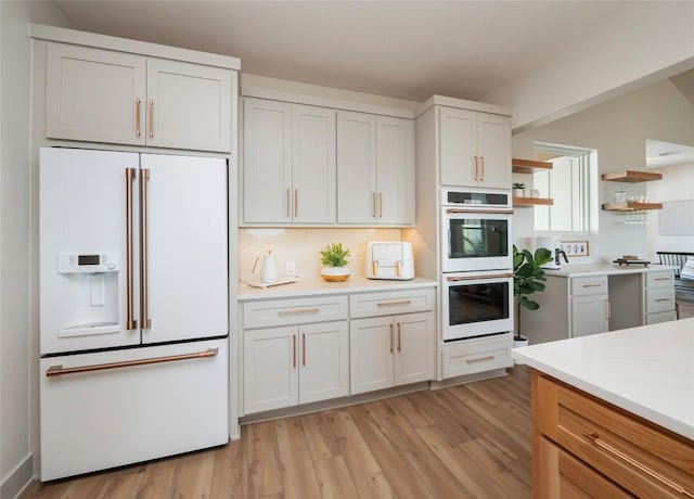 kitchen with white appliances, white cabinets, and light hardwood / wood-style floors