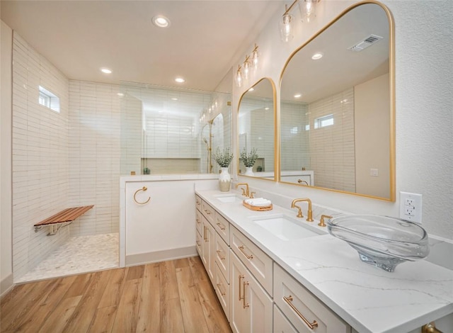 bathroom with hardwood / wood-style flooring, a tile shower, and vanity