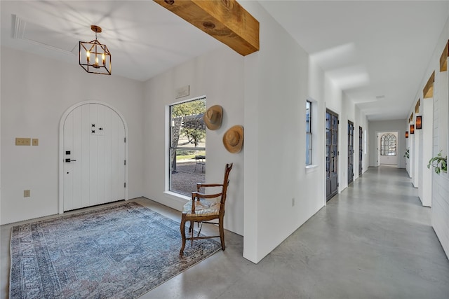 foyer entrance with a notable chandelier and concrete flooring