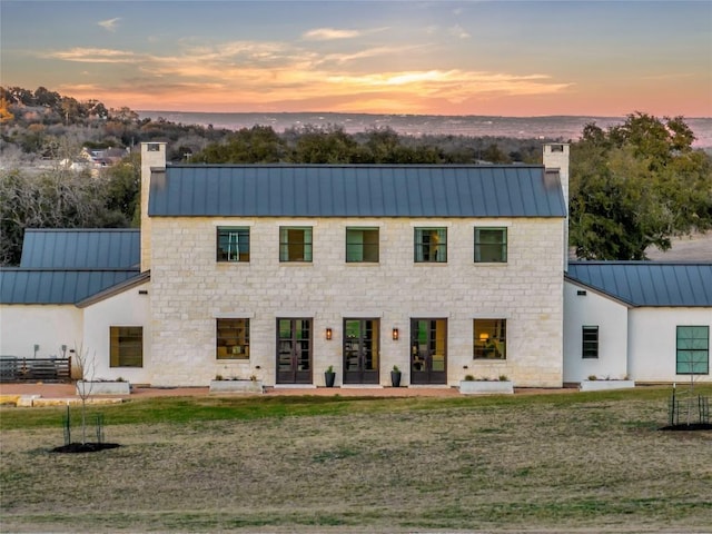 view of front facade featuring a standing seam roof, metal roof, and a chimney