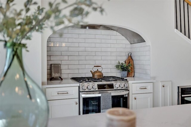 kitchen with backsplash, white cabinetry, and stainless steel appliances