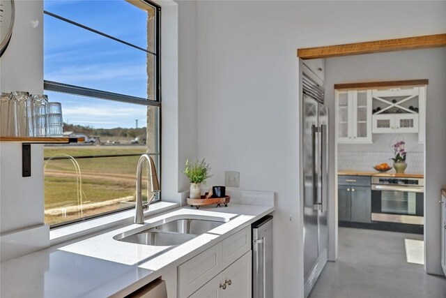 kitchen featuring white cabinetry, sink, stainless steel appliances, and a healthy amount of sunlight