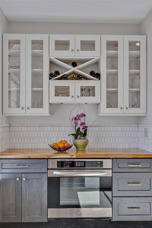 kitchen featuring white cabinets, tasteful backsplash, gray cabinetry, and double oven