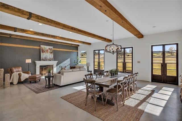 130 Overlook Dr, Fredericksburg, TX 78624 - dining area with french doors, beam ceiling, an inviting chandelier, concrete floors, and a lit fireplace