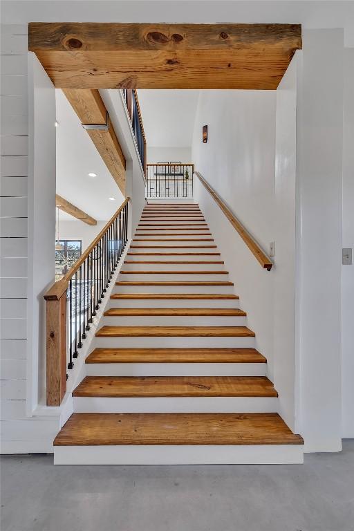 stairs with beamed ceiling and concrete floors