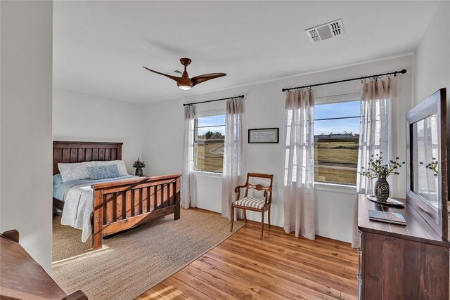 bedroom featuring light hardwood / wood-style flooring, ceiling fan, and multiple windows