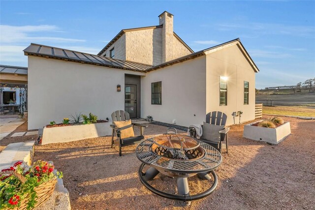 back of property with a patio area and an outdoor fire pit