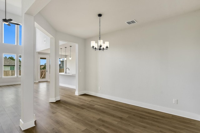 unfurnished dining area featuring ceiling fan with notable chandelier, hardwood / wood-style flooring, and sink