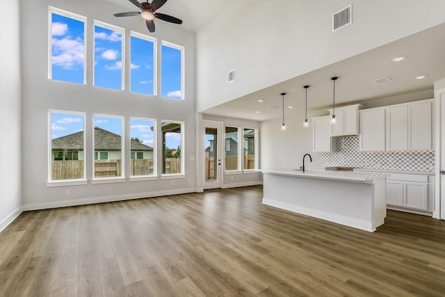 unfurnished living room with sink, a high ceiling, hardwood / wood-style floors, and ceiling fan