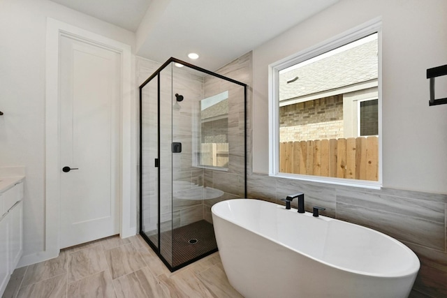 bathroom with plus walk in shower, tile walls, and vanity