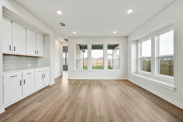 interior space featuring light hardwood / wood-style flooring, backsplash, and white cabinets