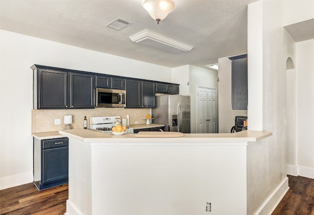 kitchen featuring backsplash, kitchen peninsula, dark wood-type flooring, and stainless steel appliances