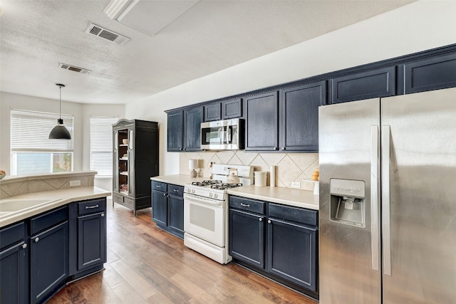 kitchen with sink, dark hardwood / wood-style floors, tasteful backsplash, decorative light fixtures, and stainless steel appliances